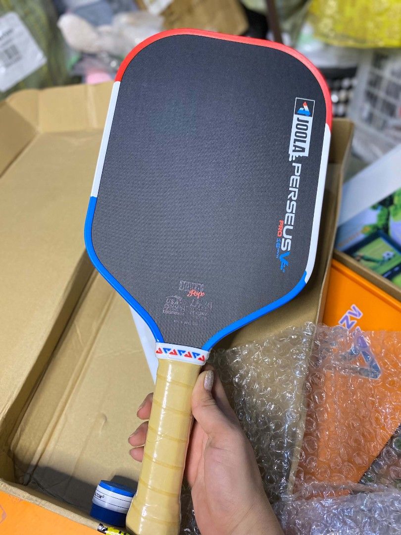 JOOLA Perseus Pro 16mm Pickleball Paddle (Category: Racket and Ball Sports) located in Taguig. Submitted by jerafelsan87737 (Listing ID 1467799887, Image 2). Description: - Model: JOOLA Perseus Pro 16mm Pickleball Paddle - Surface: Textured carbon fiber for enhanced spin control - Handle: Cushioned tan grip wrapped securely - Design: Red, white, and blue accents along the edge guard - Performance: Standard professional shape delivering exceptiona