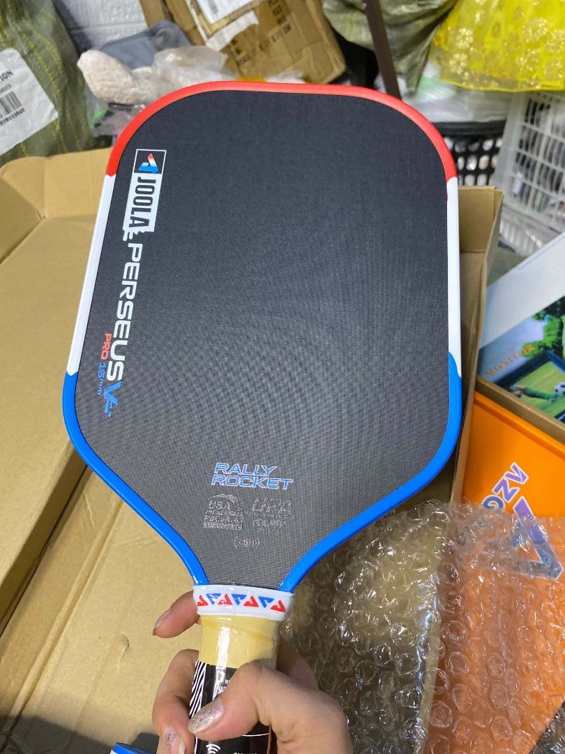 JOOLA Perseus Pro 16mm Pickleball Paddle (Category: Racket and Ball Sports) located in Taguig. Submitted by jerafelsan87737 (Listing ID 1467799887, Image 1). Description: - Model: JOOLA Perseus Pro 16mm Pickleball Paddle - Surface: Textured carbon fiber for enhanced spin control - Handle: Cushioned tan grip wrapped securely - Design: Red, white, and blue accents along the edge guard - Performance: Standard professional shape delivering exceptiona