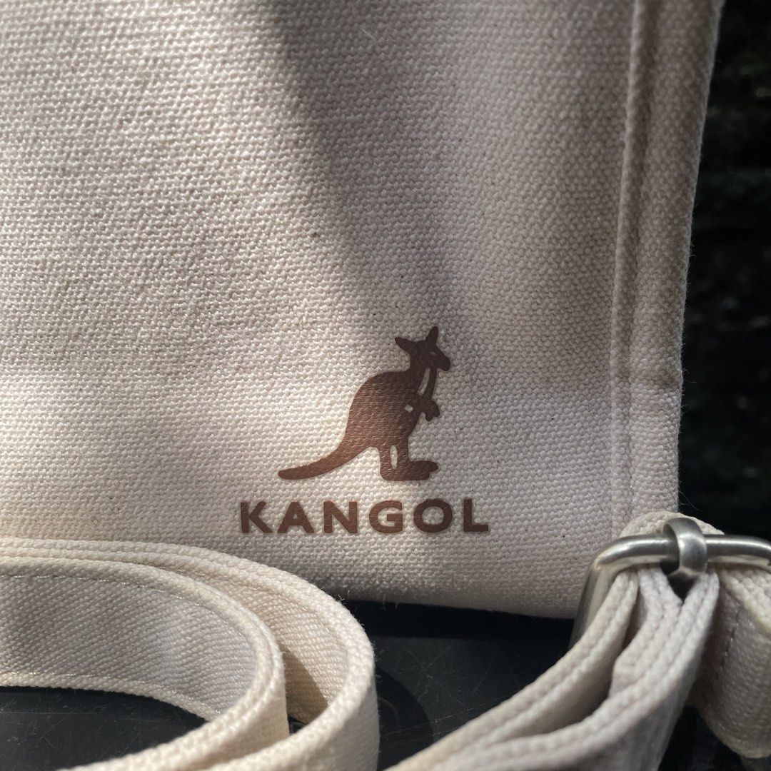 Kangol Tiny Canvas Tote Bag KNEB-TB3350 (Category: Tote Bags) located in Valenzuela. Submitted by mikayruu (Listing ID 1467642987, Image 2). Description: - Brand: Kangol - Style: Canvas Tote (Style Code: KNEB-TB3350) - Color: Ivory with brown leather-look trim and handles - Closure: Top snap button - Strap: Includes matching detachable shoulder strap - Interior: Features an official Kangol tag and slip pocket - Condition: Clean interior lining wi