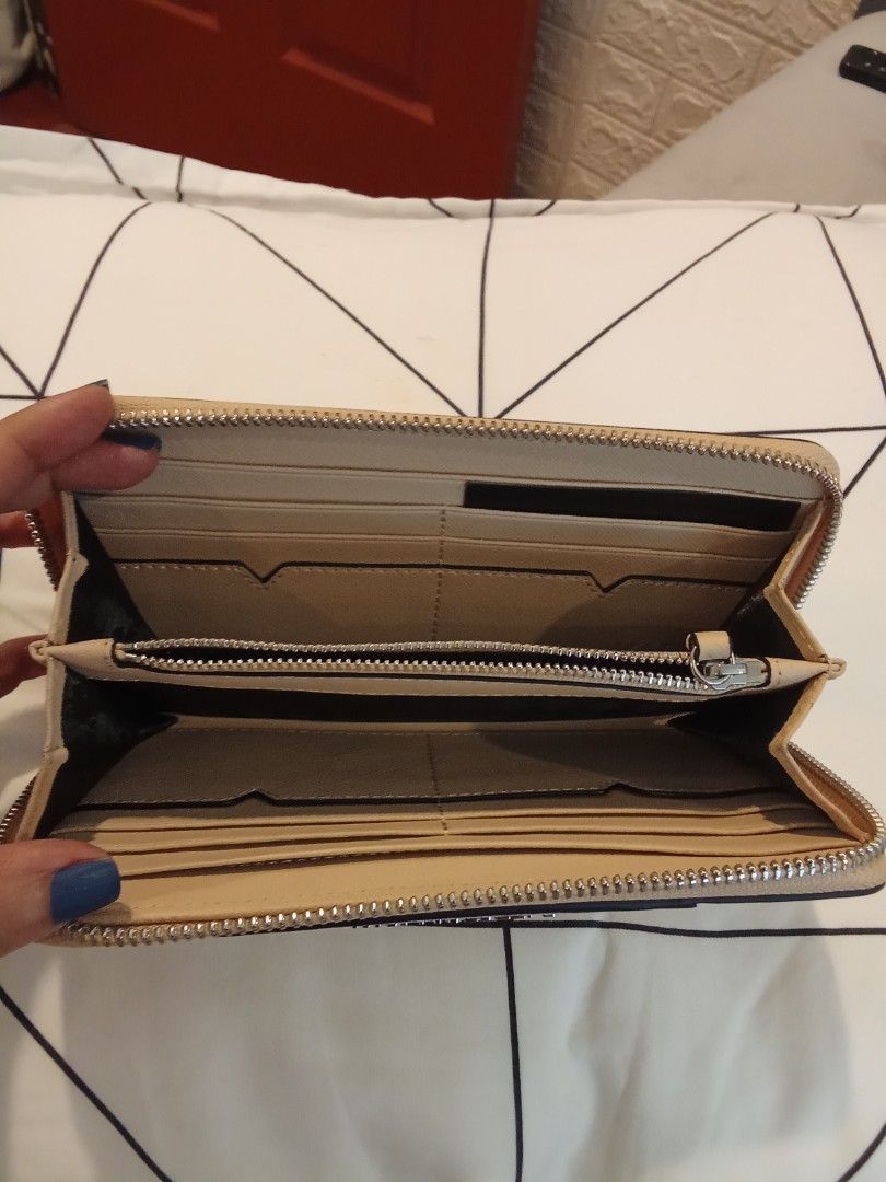 Karl Lagerfeld beige zip around wallet (Category: Wallets & Card holders) located in Las Pinas. Submitted by Gienuine (Listing ID 1467614937, Image 3). Description: - Brand: Karl Lagerfeld - Color: Elegant beige - Material: Textured faux leather with clean exterior stitching - Hardware & Branding: Striking silver metallic front branding with matching zipper pull tab - Design: Structured shape featuring a chic V-flap detail - Storage: Secure zip-a