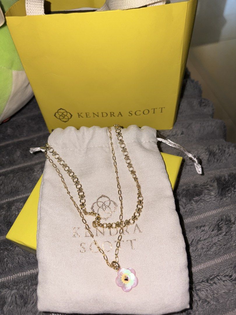 Kendra Scott Layered Flower Pendant Necklace Set (Category: Necklaces) located in Manila. Submitted by so.soiaa (Listing ID 1467680047, Image 1). Description: - Brand: Kendra Scott - Design: Gold-tone layered chain with textured links and a pink/white iridescent flower pendant - Condition: Clean, neat, and ready for gifting - Inclusions: Original fabric pouch, yellow gift box, and matching yellow paper gift bag - Perfect as an everyday accessory 