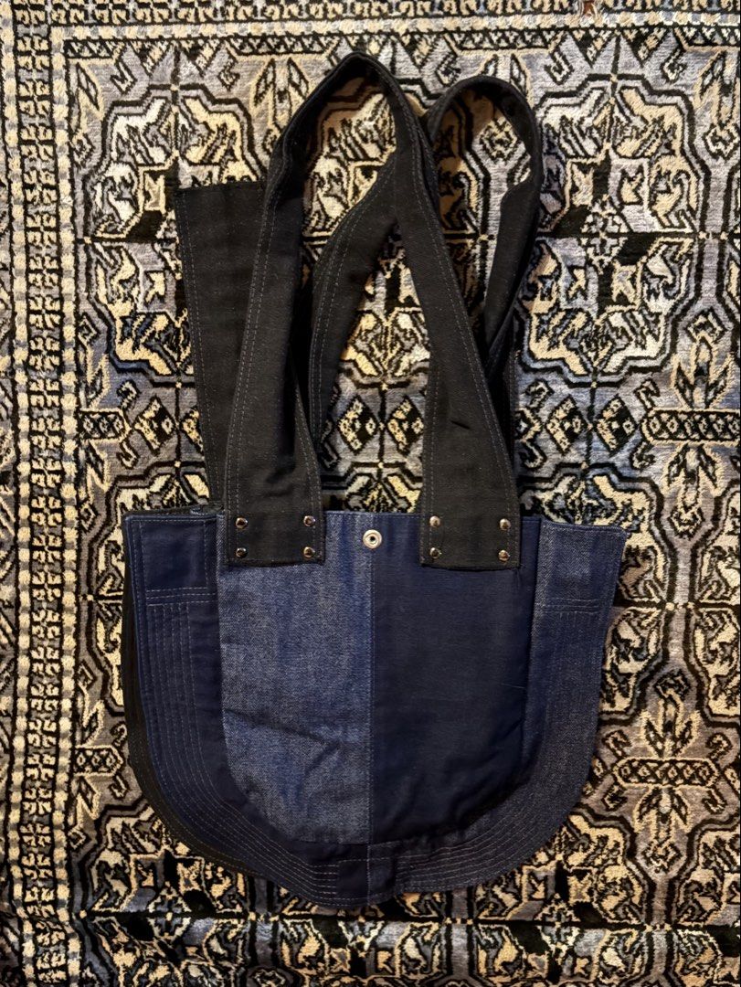 Kill Joy Studios Denim Tote Bag (Category: Tote Bags) located in San Juan City. Submitted by blueroomfinds (Listing ID 1467669994, Image 2). Description: - Brand: Kill Joy Studios - Material: Dark blue and black denim with heavy-duty construction - Details: Contrast topstitching, metal rivets, and hardware accents - Straps: Dual black denim shoulder straps secured with silver rivets - Interior: Fully lined in black with a branded red Kill Joy Stu
