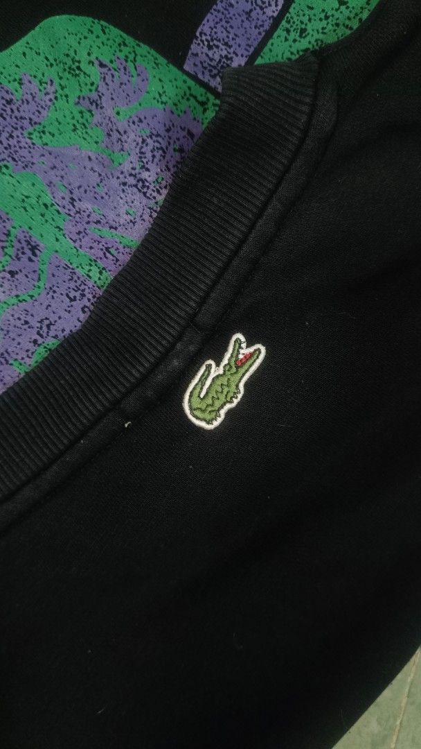 Lacoste Live Crest Sweatshirt Black Size S (Category: Coats, Jackets and Outerwear) located in Manila. Submitted by janbrix (Listing ID 1467613101, Image 3). Description: - Brand: Lacoste Live (Style Code: SH8159) - Size: S - Color: Black - Design: Large heraldic crest graphic with purple/green distressing effect and Lacoste typography on the chest - Details: Classic ribbed collar, cuffs, and hem - Condition: Clean with interior tags intact - DM 