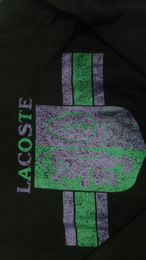 Lacoste Live Crest Sweatshirt Black Size S (Category: Coats, Jackets and Outerwear) located in Manila. Submitted by janbrix (Listing ID 1467613101, Image 2). Description: - Brand: Lacoste Live (Style Code: SH8159) - Size: S - Color: Black - Design: Large heraldic crest graphic with purple/green distressing effect and Lacoste typography on the chest - Details: Classic ribbed collar, cuffs, and hem - Condition: Clean with interior tags intact - DM 