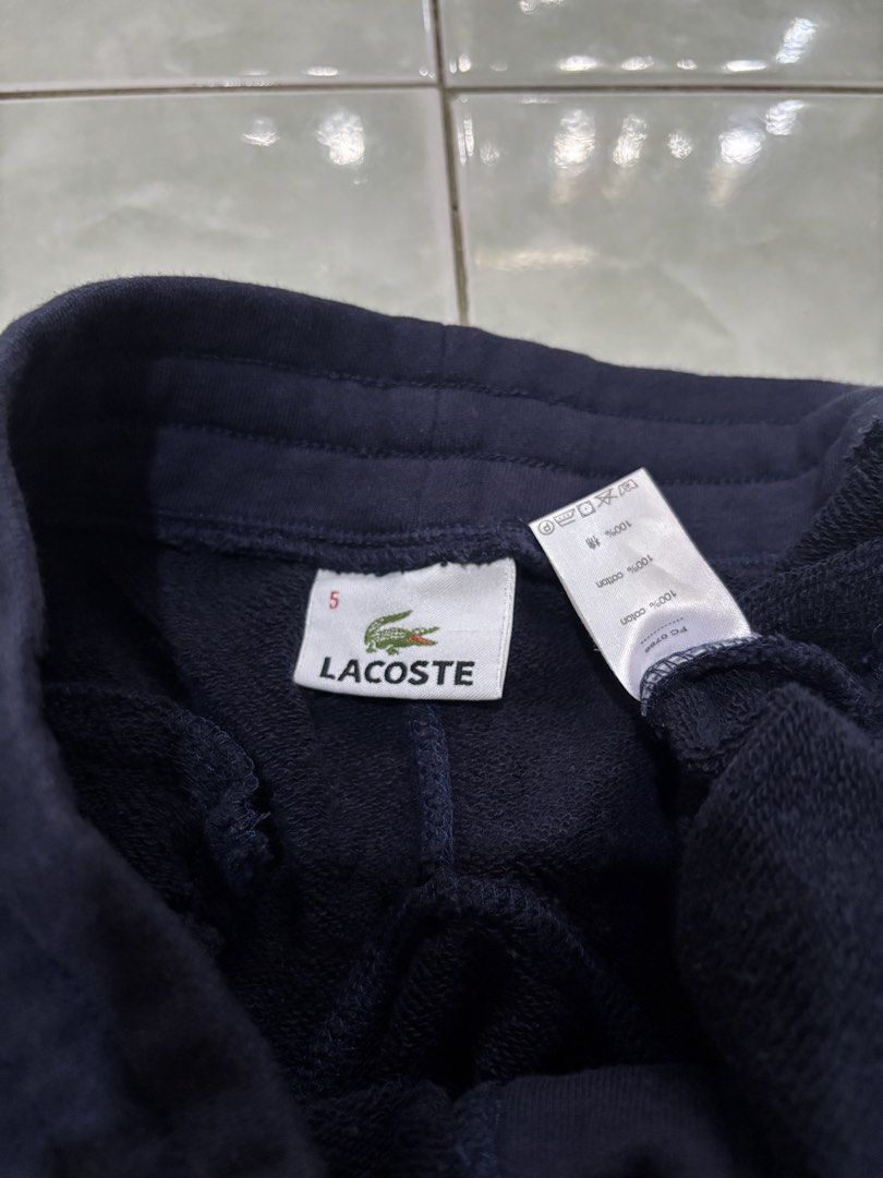 Lacoste Navy Blue Sweatshorts Size 5 (Category: Shorts) located in Daraga. Submitted by hannieldustin (Listing ID 1467634730, Image 3). Description: - Brand: Lacoste - Color: Navy Blue - Size: 5 (Tag) 28-34 waist 18 length - Material: 100% cotton with super soft French terry fleece inside - Features: Drawstring waist with metal aglets, raw cut hem, and two side pockets - Design: Circular Lacoste patch logo on the left leg with three embroidered s