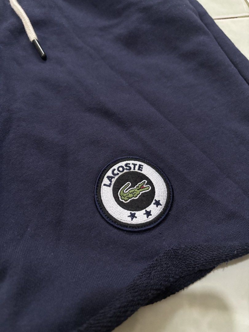 Lacoste Navy Blue Sweatshorts Size 5 (Category: Shorts) located in Daraga. Submitted by hannieldustin (Listing ID 1467634730, Image 2). Description: - Brand: Lacoste - Color: Navy Blue - Size: 5 (Tag) 28-34 waist 18 length - Material: 100% cotton with super soft French terry fleece inside - Features: Drawstring waist with metal aglets, raw cut hem, and two side pockets - Design: Circular Lacoste patch logo on the left leg with three embroidered s