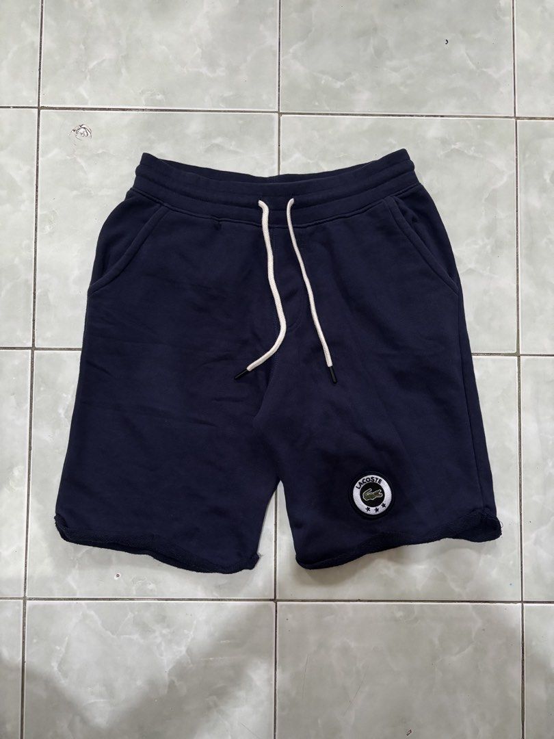 Lacoste Navy Blue Sweatshorts Size 5 (Category: Shorts) located in Daraga. Submitted by hannieldustin (Listing ID 1467634730, Image 1). Description: - Brand: Lacoste - Color: Navy Blue - Size: 5 (Tag) 28-34 waist 18 length - Material: 100% cotton with super soft French terry fleece inside - Features: Drawstring waist with metal aglets, raw cut hem, and two side pockets - Design: Circular Lacoste patch logo on the left leg with three embroidered s