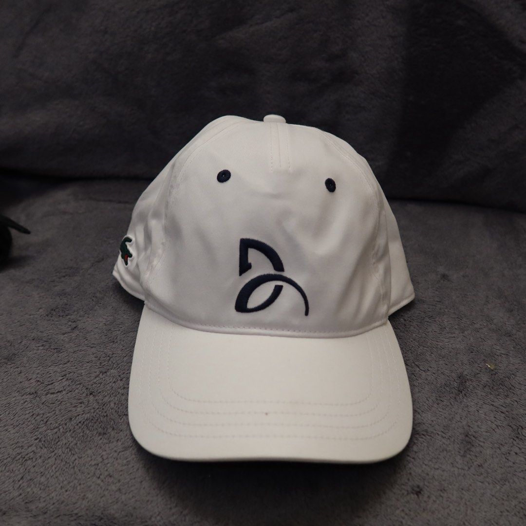 Lacoste Sport White Tennis Cap (Category: Caps & Hats) located in Manila. Submitted by gentlewind_62f064 (Listing ID 1467616936, Image 1). Description: - Brand: Lacoste Sport - Model: TH1044 - Color: White with navy blue embroidered branding - Logo: Iconic green crocodile patch on the side - Size: One size fits all (adjustable strap in the back) - Condition: Clean inside and out, ready to wear.