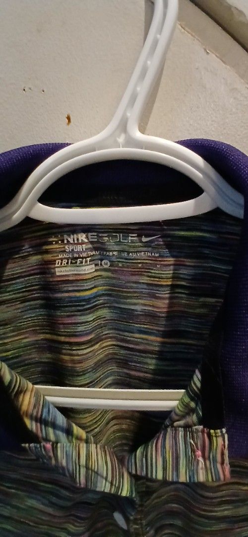Ladies golf shirt Medium (Category: Activewear) located in Marikina City. Submitted by darthvader888 (Listing ID 1467730577, Image 2). Description: - Brand: Nike Golf - Size: Medium (M) - Design: Multi-colored striped pattern with a purple collar and front buttons - Technology: Dri-Fit fabric keeps you dry and comfortable - Features: Lightweight material and embroidered Nike swoosh logo near the collar - Condition: Great addition to any golfing w