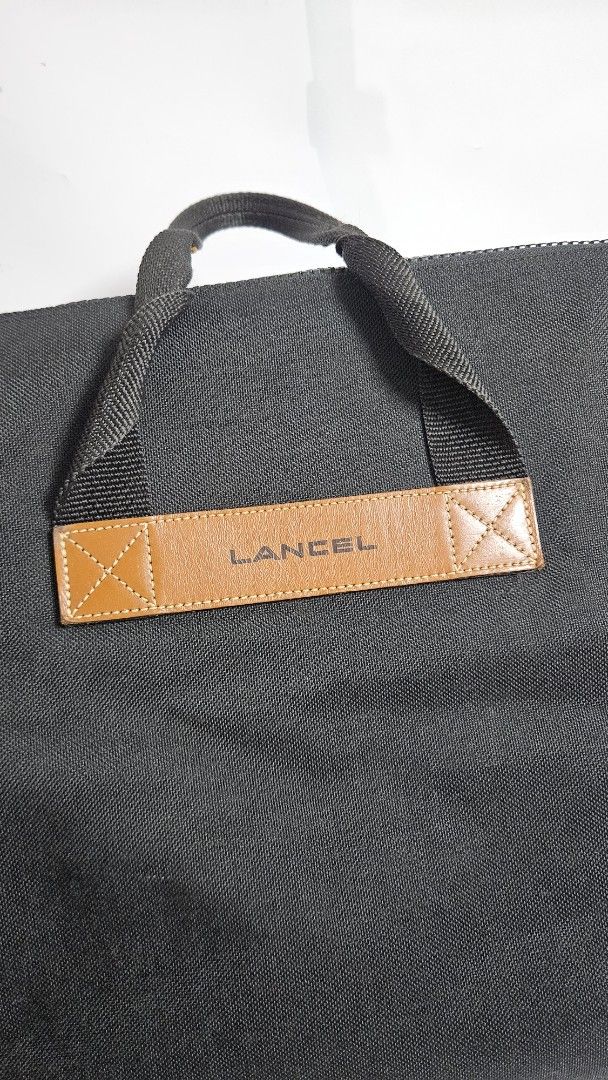 Lancel Paris Black Canvas Tote Bag (Category: Tote Bags) located in Alfonso. Submitted by jbcamet (Listing ID 1467711202, Image 2). Description: - Brand: Lancel Paris - Material: Durable black canvas with brown leather handles - Details: Embossed Lancel branding on leather accent - Closure: Secure zippered main closure - Interior: Spacious fabric lining with an inner zip pocket - Condition: Clean and practical design, sturdy construction - Style: