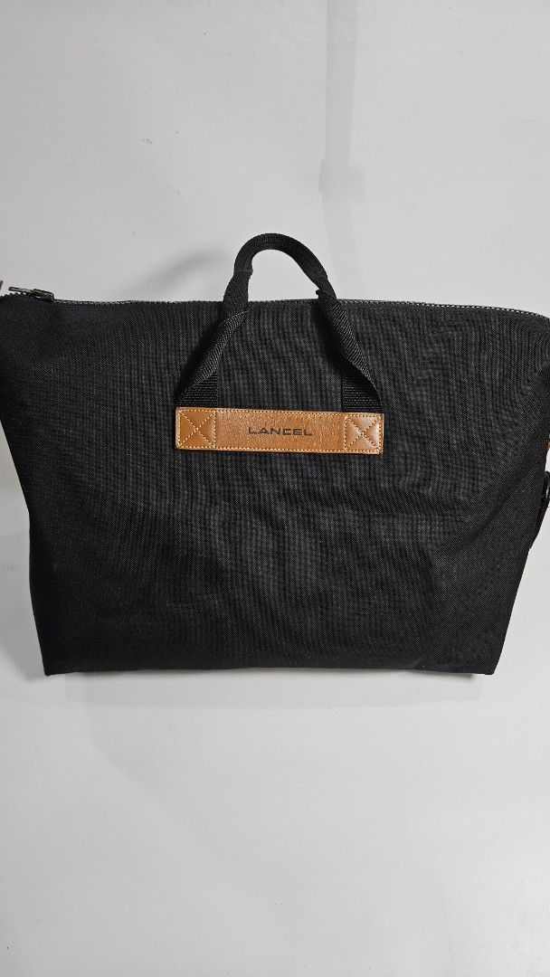 Lancel Paris Black Canvas Tote Bag (Category: Tote Bags) located in Alfonso. Submitted by jbcamet (Listing ID 1467711202, Image 1). Description: - Brand: Lancel Paris - Material: Durable black canvas with brown leather handles - Details: Embossed Lancel branding on leather accent - Closure: Secure zippered main closure - Interior: Spacious fabric lining with an inner zip pocket - Condition: Clean and practical design, sturdy construction - Style: