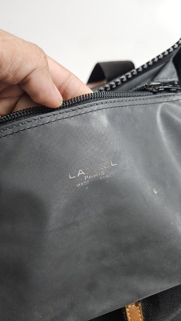 Lancel Paris Black Canvas Tote Bag (Category: Tote Bags) located in Alfonso. Submitted by jbcamet (Listing ID 1467711202, Image 3). Description: - Brand: Lancel Paris - Material: Durable black canvas with brown leather handles - Details: Embossed Lancel branding on leather accent - Closure: Secure zippered main closure - Interior: Spacious fabric lining with an inner zip pocket - Condition: Clean and practical design, sturdy construction - Style: