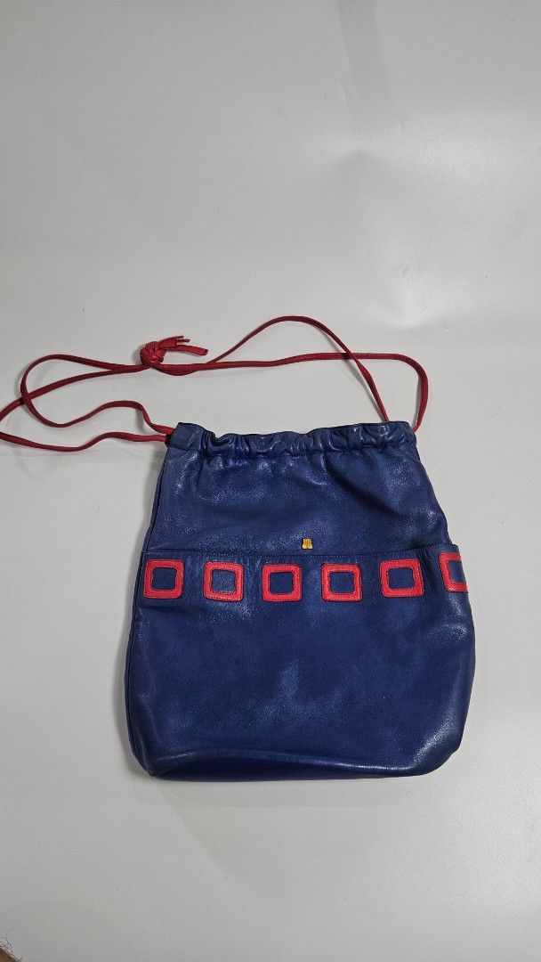 Lanvin Paris Blue Leather Drawstring Bucket Bag (Category: Luxury Bags & Wallets) located in Alfonso. Submitted by jbcamet (Listing ID 1467710465, Image 1). Description: - Brand: Lanvin Paris (Made in France) - Material: Premium royal blue leather with tan textured leather interior - Design: Eye-catching red square applique details down the front with gold-tone hardware and small logo accent - Closure: Red drawstring closure - Interior: Includes 