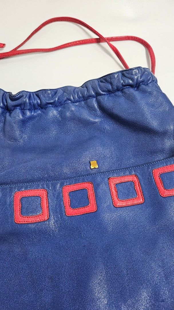Lanvin Paris Blue Leather Drawstring Bucket Bag (Category: Luxury Bags & Wallets) located in Alfonso. Submitted by jbcamet (Listing ID 1467710465, Image 2). Description: - Brand: Lanvin Paris (Made in France) - Material: Premium royal blue leather with tan textured leather interior - Design: Eye-catching red square applique details down the front with gold-tone hardware and small logo accent - Closure: Red drawstring closure - Interior: Includes 