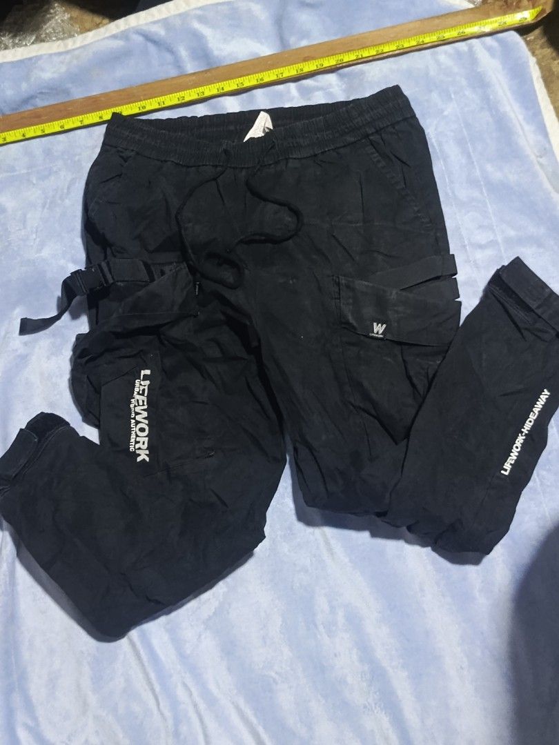 LifeWork Black Cargo Pants Medium (Category: Jeans) located in City of Isabela. Submitted by warmbird.d06e6f (Listing ID 1467637808, Image 2). Description: - Brand: LifeWork - Color: Black - Size: Medium - Style: Streetwear - Material: Durable cotton-blend - Features: Multiple utility pockets with straps, brand logo patches, text print down the leg - Fit: Adjustable drawstring waistband and Velcro ankle cuffs - Condition: Brand new / Excellent.