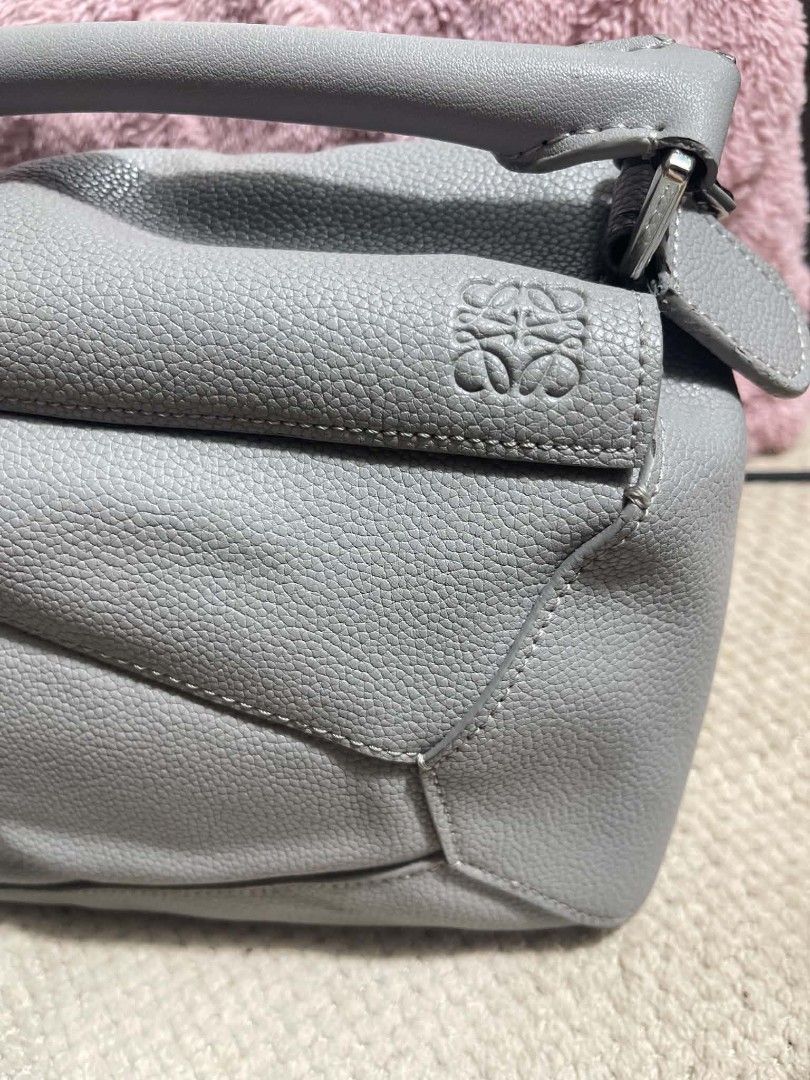 Loewe Grey Leather bag (Category: Shoulder Bags) located in Manila. Submitted by jjm-collections (Listing ID 1467642245, Image 2). Description: - Loewe Puzzle bag in versatile grey pebbled leather - Iconic geometric panel design with top handle and zip closure - Includes matching wide shoulder strap with repeated anagram branding - Clean interior featuring herringbone fabric lining and leather brand patch - Made in Spain with heat-stamped serial 