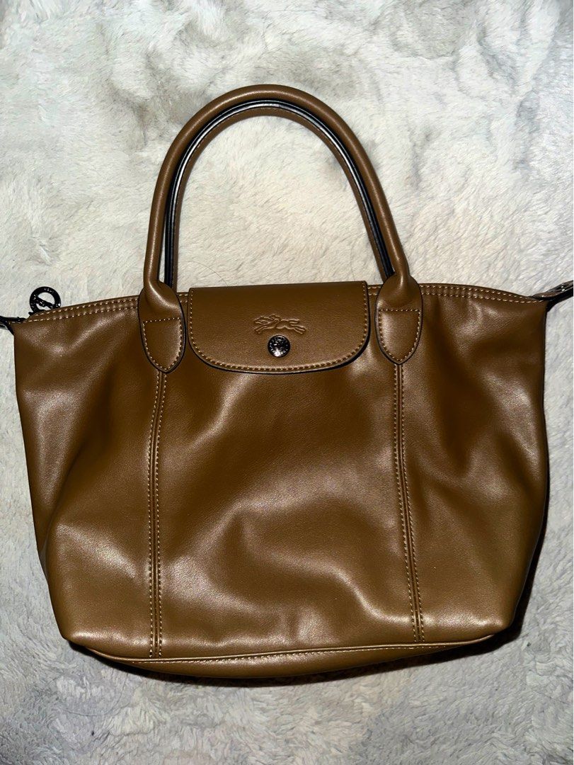 Longchamp Brown Leather Top Handle Bag (Category: Luxury Bags & Wallets) located in Taguig. Submitted by fort22 (Listing ID 1467793986, Image 1). Description: - Brand: Longchamp - Material: Premium brown leather with elegant contrast white stitching - Closure: Secure top zipper with logo pull tab + front flap with snap closure and embossed jockey logo - Interior: Clean patterned fabric lining with a convenient zip pocket - Inclusion: Adjustable a