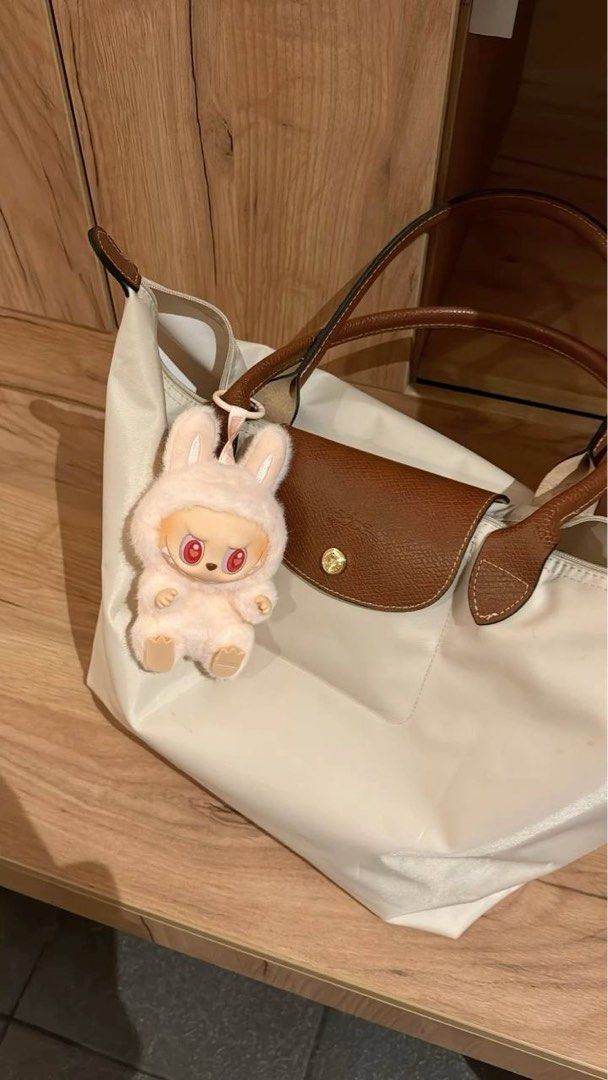 Longchamp Le Pliage Nylon Tote Bag Cream (Category: Luxury Bags & Wallets) located in Paranaque City. Submitted by ciangggg (Listing ID 1467836321, Image 2). Description: - NGA Longchamp Le Pliage tote bag - Color: Cream nylon with brown leather handles and flap - Classic foldable design with zip top and snap closure - Spacious interior, fits all your daily essentials - Clean interior and great overall structure - Comes with a free cute pink bunn
