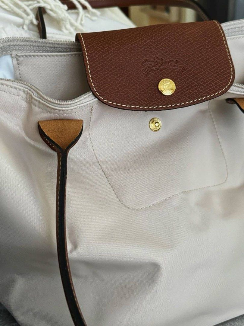 Longchamp Le Pliage Nylon Tote Bag Cream (Category: Luxury Bags & Wallets) located in Paranaque City. Submitted by ciangggg (Listing ID 1467836321, Image 3). Description: - NGA Longchamp Le Pliage tote bag - Color: Cream nylon with brown leather handles and flap - Classic foldable design with zip top and snap closure - Spacious interior, fits all your daily essentials - Clean interior and great overall structure - Comes with a free cute pink bunn