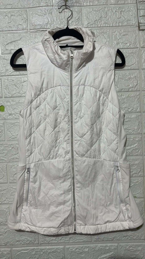 Lululemon White Quilted Puffer Vest (Category: Coats, Jackets and Outerwear) located in Manila. Submitted by grandwater.53a8ce (Listing ID 1467666720, Image 1). Description: - Brand: Lululemon - Style: Quilted puffer vest - Color: White - Closure: Full zip front with high collar - Pockets: Two secure zippered side pockets with branded pulls - Comfort: Soft side panels for easy movement - Details: Iconic reflective omega logo on the lower back - C