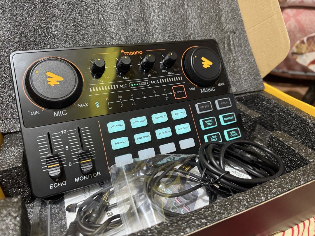 Maono Podcast Audio Interface Mixer Sound Board (Category: Soundbars, Speakers & Amplifiers) located in Manila. Submitted by apol_brugada (Listing ID 1467745622, Image 2). Description: Maono audio interface mixer for streaming and recording. Knobs for mic, music, echo, and monitor levels. Multiple sound effect buttons like applause, laughter, and cheering. Bluetooth enabled with pitch and denoise options. Included in the box are all original cabl