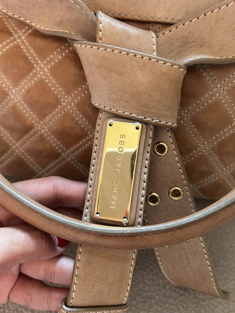 Marc Jacobs Quilted Leather Handbag Brown (Category: Luxury Bags & Wallets) located in Cavite. Submitted by florabells (Listing ID 1467694850, Image 2). Description: - Brand: Marc Jacobs - Material: Premium brown leather with quilted diamond pattern - Hardware: Elegant gold-tone with front lock closure detail - Closure: Secure zip-top closure - Handles: Sturdy top handles with integrated buckle strap design - Interior: Clean lining with a spaciou