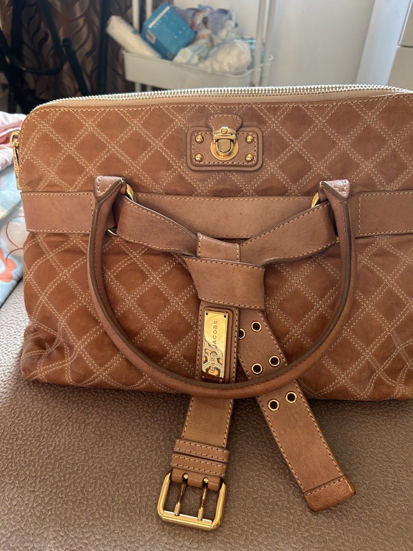 Marc Jacobs Quilted Leather Handbag Brown (Category: Luxury Bags & Wallets) located in Cavite. Submitted by florabells (Listing ID 1467694850, Image 1). Description: - Brand: Marc Jacobs - Material: Premium brown leather with quilted diamond pattern - Hardware: Elegant gold-tone with front lock closure detail - Closure: Secure zip-top closure - Handles: Sturdy top handles with integrated buckle strap design - Interior: Clean lining with a spaciou