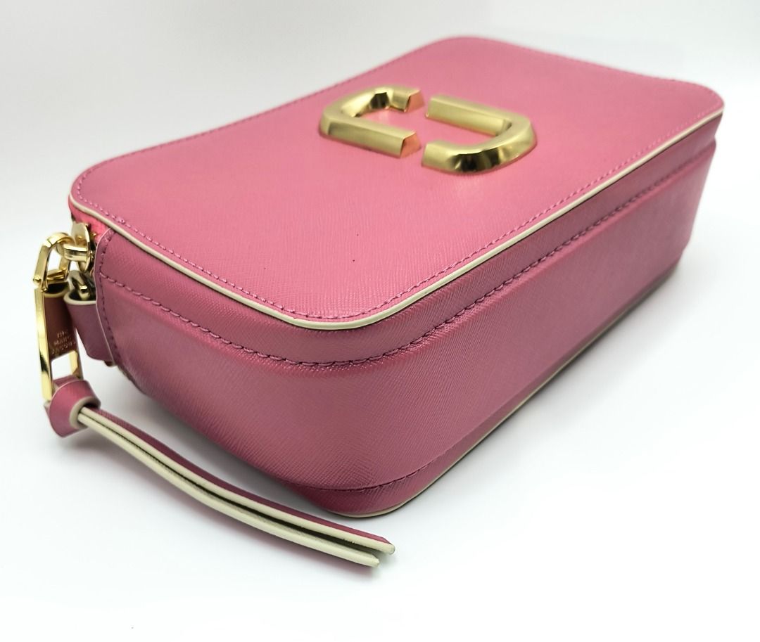Marc Jacobs The Sure Shot Camera Bag - Pink (Category: Luxury Bags & Wallets) located in Cebu City. Submitted by affordabagss (Listing ID 1467788655, Image 2). Description: Marc Jacobs The Sure Shot camera bag crafted in pink Saffiano leather with contrasting cream and white accents and gold-tone hardware. Features the signature Double J logo, dual top zip compartments, detachable and adjustable woven shoulder strap, and rear slip pocket. Finishe