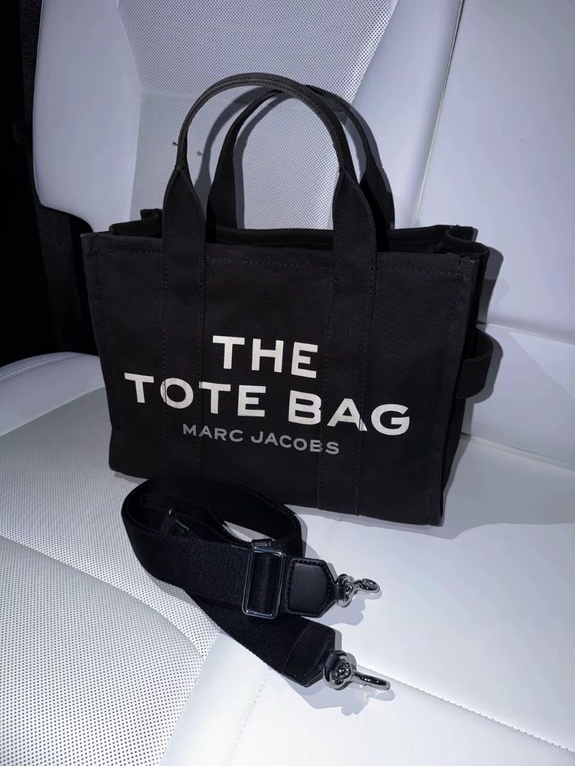 Marc Jacobs The Tote Bag Black Canvas (Category: Luxury Bags & Wallets) located in Quezon City. Submitted by mofu1 (Listing ID 1467772200, Image 3). Description: - Brand: Marc Jacobs - Material: Durable black canvas with signature white lettering - Versatile carry: Includes matching top handles and a removable, adjustable shoulder strap - Design: Structured shape with chic side strap details - Back details: Authentic brand patch with style info a