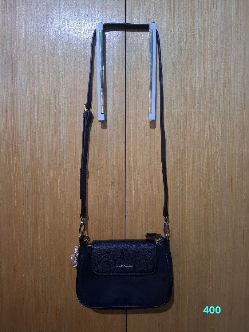 Matthews black nylon crossbody bag (Category: Cross-body Bags) located in Pasay City. Submitted by emilia1102 (Listing ID 1467794479, Image 1). Description: - Brand: Matthews - Color: Classic Black - Material: Soft nylon body with a structured base - Closure: Top zip closure plus a front flap pocket with a textured accent - Hardware: Premium gold-tone details - Strap: Long and fully adjustable - Size: Compact and lightweight, perfect for daily es