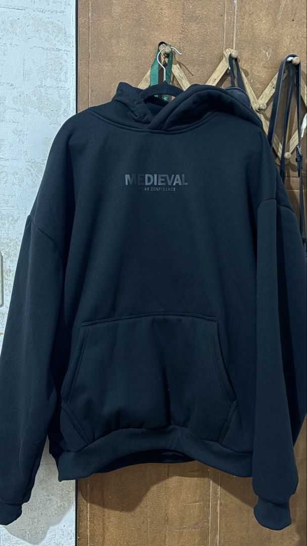 Medieval Black Hoodie (Category: Coats, Jackets and Outerwear) located in Pagsanjan. Submitted by dinsyllllll (Listing ID 1467743018, Image 2). Description: - Brand: Medieval - Color: Black - Size 3xl - Material: Heavyweight cotton - Fit: Oversized through shoulders and body - Design: Small front chest logo and bold large back print - Features: Kangaroo pocket, ribbed cuffs/hem, and thick drawstring-free hood - Style: Essential streetwear piece t