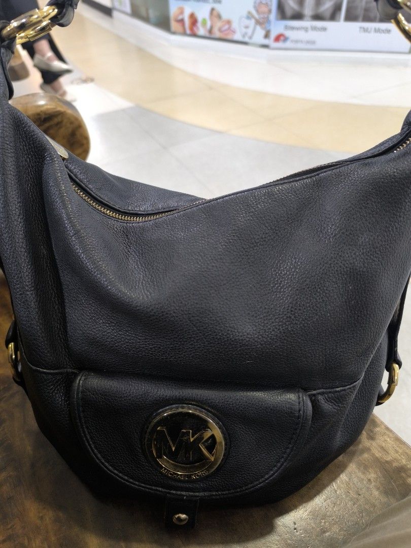 Michael Kors Black Leather Shoulder Bag (Category: Luxury Bags & Wallets) located in Baguio. Submitted by tifay27 (Listing ID 1467720131, Image 2). Description: - Brand: Michael Kors - Material: Premium black pebble leather - Hardware: Gold-toned throughout with prominent front MK circular logo plaque - Closure: Secure top zipper closure - Features: Front flap pocket, comfortable single shoulder strap with gold rings, and structured base for extr