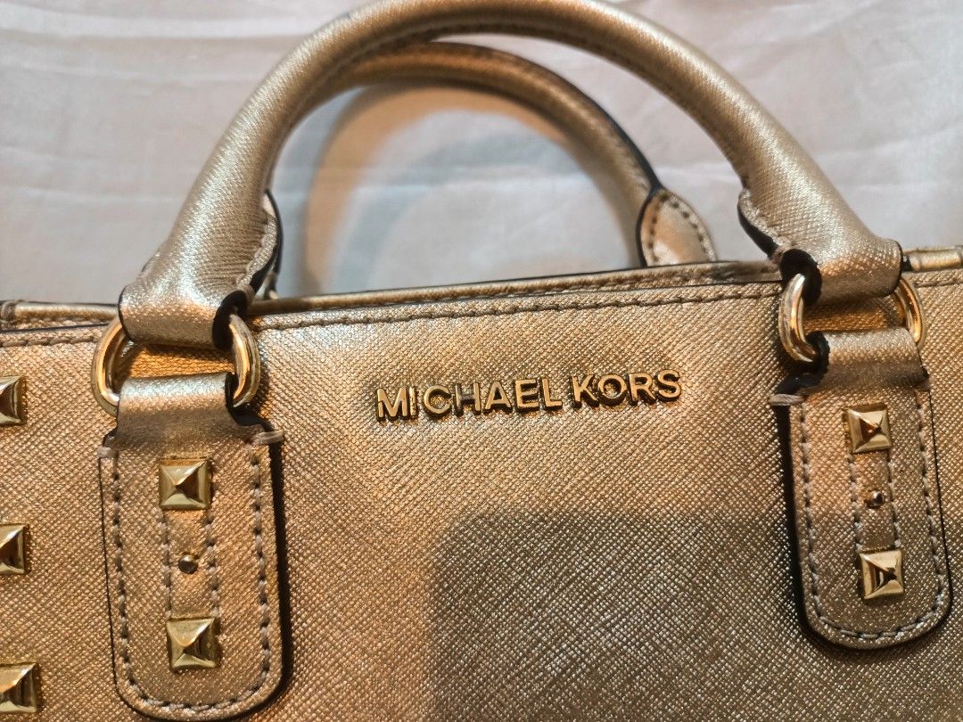 Michael Kors Gold Studded Tote Handbag (Category: Luxury Bags & Wallets) located in Manila. Submitted by preloved439 (Listing ID 1467234876, Image 3). Description: - Authentic Michael Kors Sandrine - Structured design with durable dual top handles - Stylish gold-tone pyramid studs along the front - Open top with a convenient zipped main compartment - Compact yet spacious enough for daily essentials - Crafted from clean, durable Saffiano-style lea