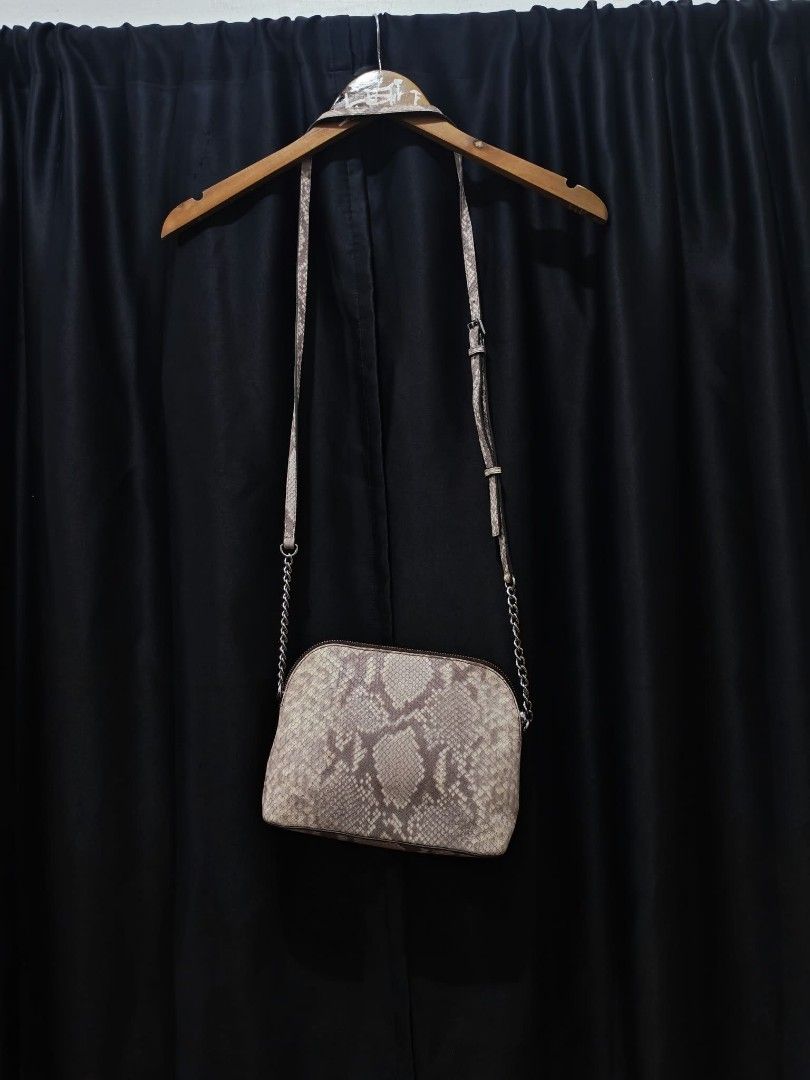 Michael Kors Python Print Crossbody Bag (Category: Cross-body Bags) located in Baguio. Submitted by solo_ukay (Listing ID 1467786916, Image 2). Description: Michael Kors crossbody bag in a python snakeskin print. Silver-toned hardware plaque on the front with Michael Kors Est. 1981 lettering. Zip-top closure leading to a branded fabric interior lining with a slip pocket. Adjustable strap with chain links on the lower sections. Shows some interior