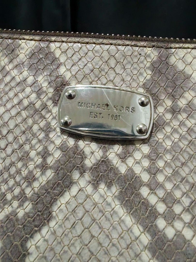 Michael Kors Python Print Crossbody Bag (Category: Cross-body Bags) located in Baguio. Submitted by solo_ukay (Listing ID 1467786916, Image 3). Description: Michael Kors crossbody bag in a python snakeskin print. Silver-toned hardware plaque on the front with Michael Kors Est. 1981 lettering. Zip-top closure leading to a branded fabric interior lining with a slip pocket. Adjustable strap with chain links on the lower sections. Shows some interior