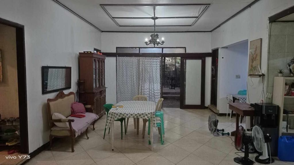 Multi-storey house with yard and garage space (Category: Lot) located in Quezon City. Submitted by epicdragon.28c6f5 (Listing ID 1467611802, Image 2). Description: - Multi-level house layout with a secure front gate and balcony - Convenient open garage area on the ground floor - Dining setup with a patterned tablecloth, vintage sofa, and elegant chandelier included - Scenic outdoor space featuring garden beds, trees, and a block wall fence - RUSH