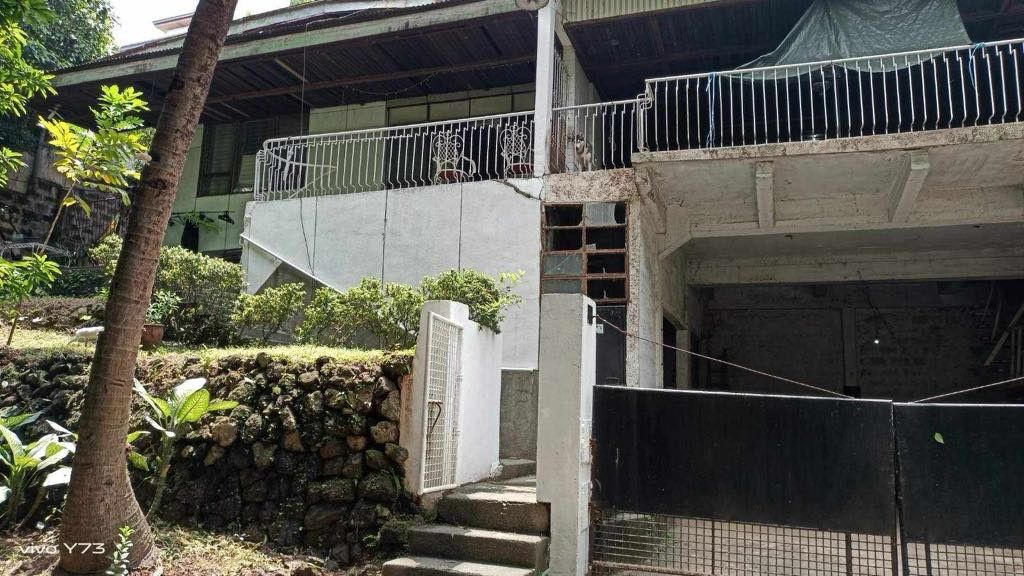 Multi-storey house with yard and garage space (Category: Lot) located in Quezon City. Submitted by epicdragon.28c6f5 (Listing ID 1467611802, Image 1). Description: - Multi-level house layout with a secure front gate and balcony - Convenient open garage area on the ground floor - Dining setup with a patterned tablecloth, vintage sofa, and elegant chandelier included - Scenic outdoor space featuring garden beds, trees, and a block wall fence - RUSH