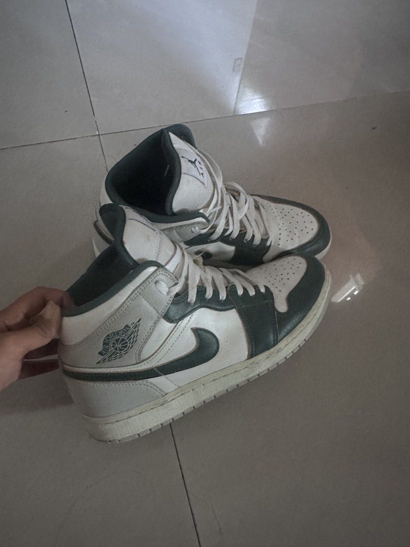 Nike Air Jordan 1 Sneakers (Category: Sneakers) located in San Miguel. Submitted by monicakettle (Listing ID 1467663151, Image 3). Description: - Model: Air Jordan 1 Mid - Colorway: White and Dark Navy Green - Design: Classic high-top silhouette with perforated toe box, signature swoosh, Jumpman tongue logo, and stamped Wings logo - Condition: Normal wear on soles and creases on the toe box - Perfect as a solid everyday rotation pair.