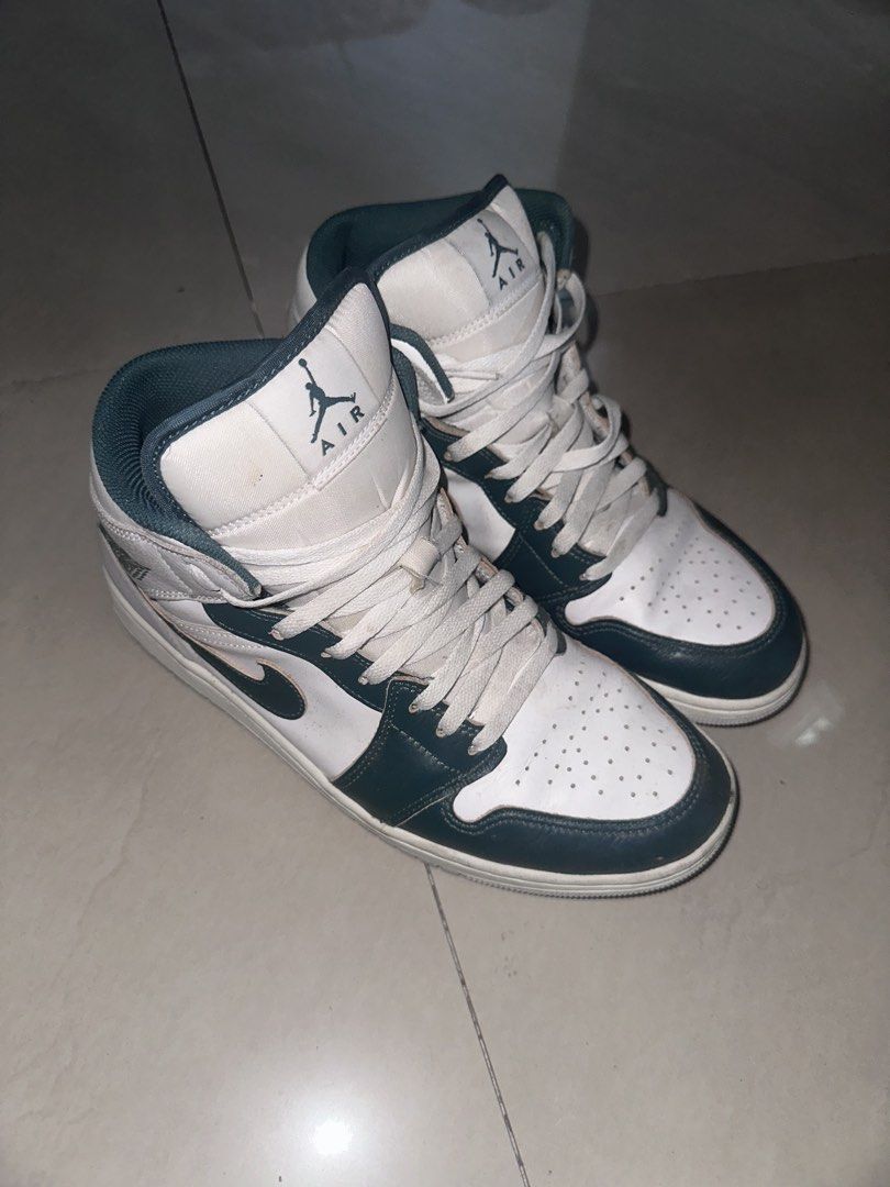 Nike Air Jordan 1 Sneakers (Category: Sneakers) located in San Miguel. Submitted by monicakettle (Listing ID 1467663151, Image 1). Description: - Model: Air Jordan 1 Mid - Colorway: White and Dark Navy Green - Design: Classic high-top silhouette with perforated toe box, signature swoosh, Jumpman tongue logo, and stamped Wings logo - Condition: Normal wear on soles and creases on the toe box - Perfect as a solid everyday rotation pair.