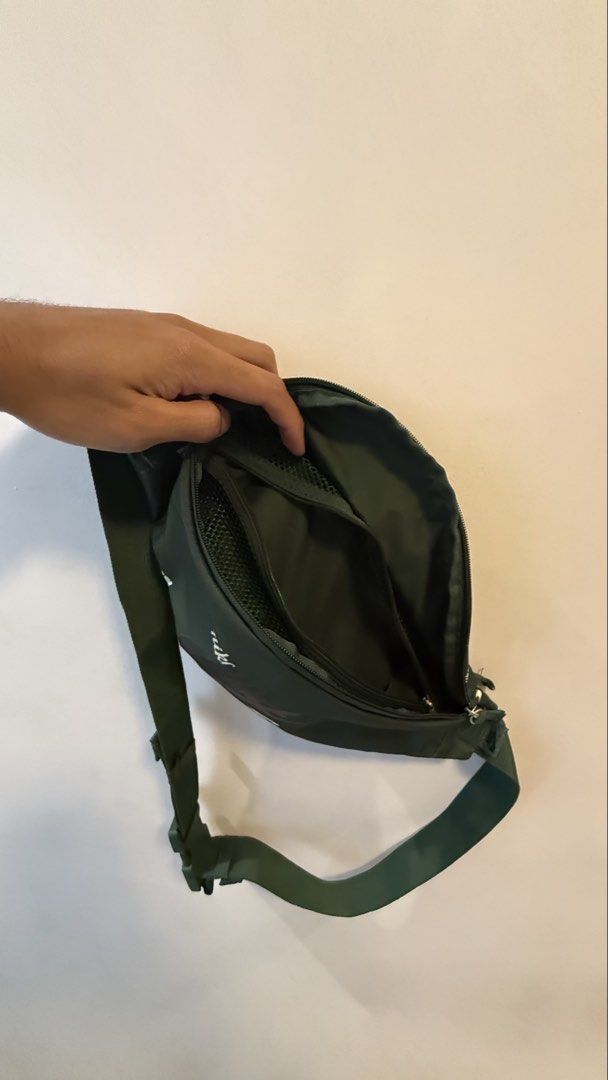 Nike Green Crossbody Bag (Category: Sling Bags) located in Quezon City. Submitted by kobeeeee_12 (Listing ID 1467736304, Image 3). Description: - Brand: Nike - Color: Dark green with white all-over brand text prints - Material: 100% polyester - Closure: Secure zipper - Strap: Adjustable with durable plastic buckle - Interior: Fabric lining with handy mesh pockets - Condition: Clean tag visible inside - Size: Compact and convenient for daily essen