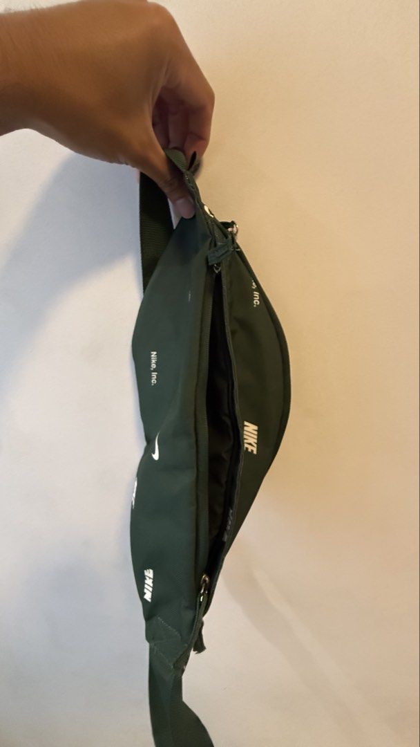 Nike Green Crossbody Bag (Category: Sling Bags) located in Quezon City. Submitted by kobeeeee_12 (Listing ID 1467736304, Image 2). Description: - Brand: Nike - Color: Dark green with white all-over brand text prints - Material: 100% polyester - Closure: Secure zipper - Strap: Adjustable with durable plastic buckle - Interior: Fabric lining with handy mesh pockets - Condition: Clean tag visible inside - Size: Compact and convenient for daily essen