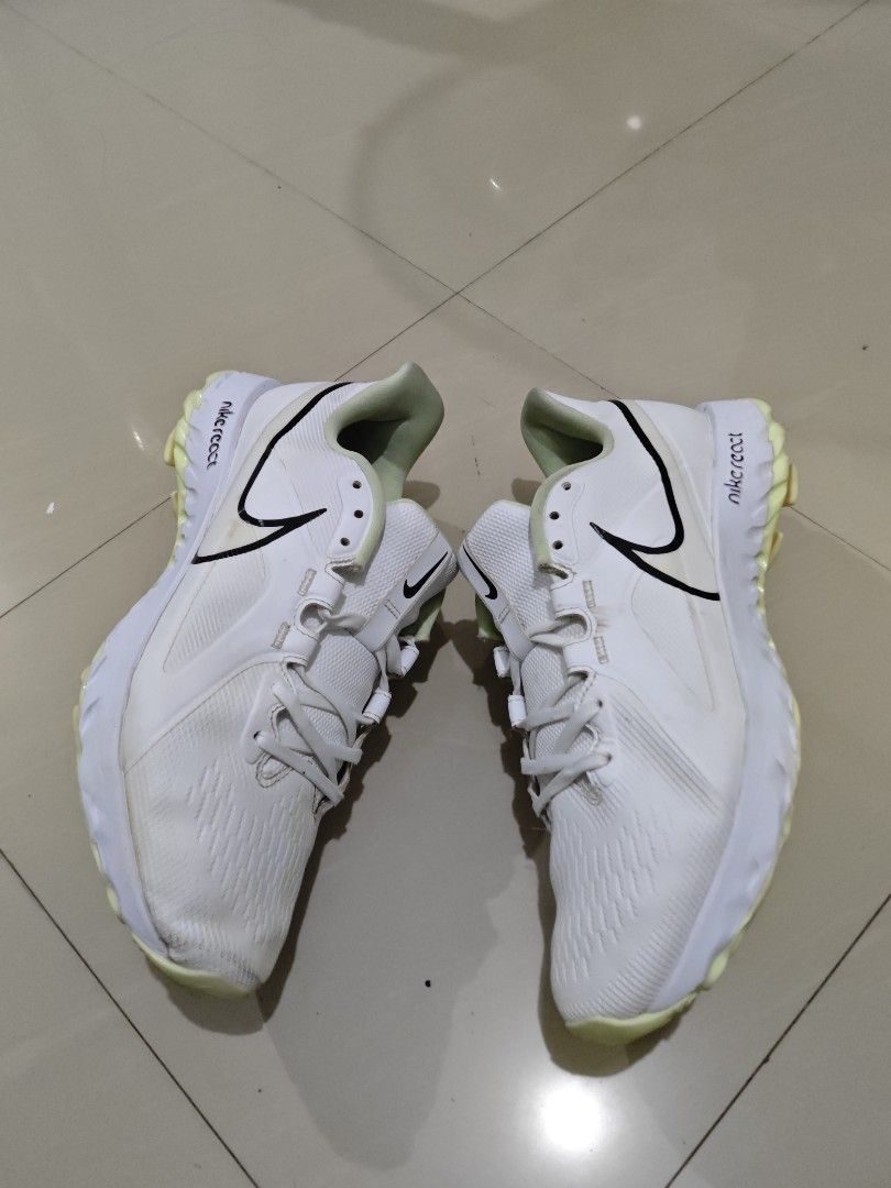 Nike React White Spikeless golfshoes (Category: Sneakers) located in Davao. Submitted by judelabust72026 (Listing ID 1467748071, Image 1). Description: - Brand: Nike React Turf Football Boots - Colorway: White with black swoosh logos and neon yellow soles/heel accents - Closure: Lace-up with centered Nike branding - Condition: Uppers are clean overall; outer soles show minor dirt from previous turf play - Performance: Responsive React cushioning,