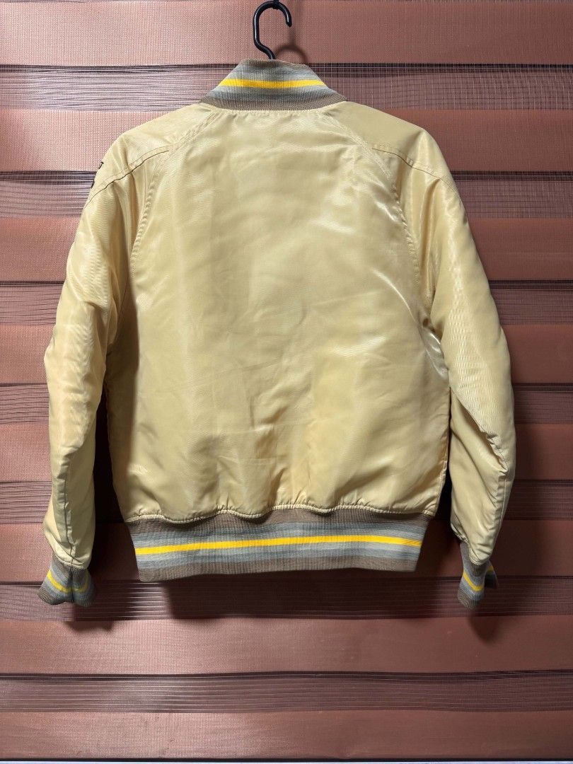 Nike Sportswear Essentials Varsity Bomber Jacket (Category: Coats, Jackets and Outerwear) located in Makati City. Submitted by rexb1993 (Listing ID 1467670747, Image 3). Description: - Brand: Nike Sportswear - Color: Beige and Yellow - Closure: Button-up front - Details: Striped ribbed collar, cuffs, and hem; 'NS RL' chenille embroidery; 'NSW' sleeve text; 'Advanced Project Testing Team' patch - Measurements: Width 21 inches, Length 25 inches - M