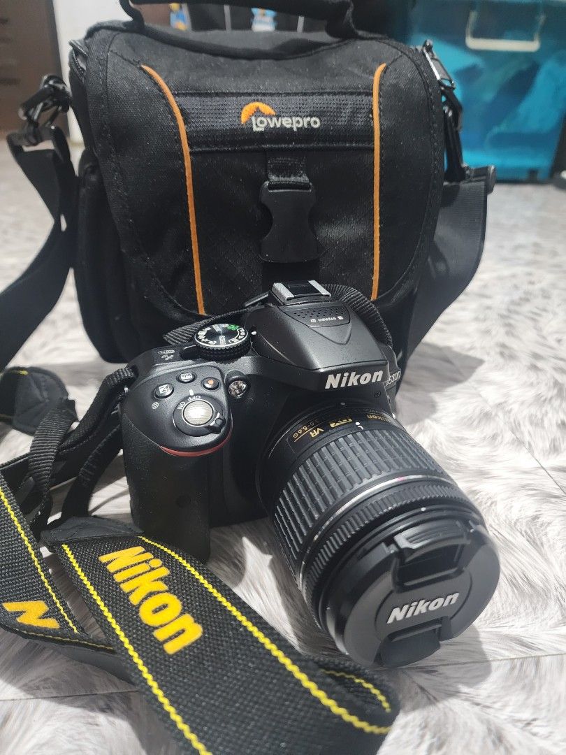 Nikon D5300 Camera with Lens and Lowepro Bag (Category: Cameras) located in Valenzuela. Submitted by sunshinebucud (Listing ID 1467660749, Image 1). Description: - Nikon DSLR camera body and zoom lens ready for shooting - Includes Nikon neck strap and padded Lowepro shoulder bag - Fully functional setup with clean optics and responsive buttons - Battery door is completely intact - Minor cosmetic scuffs around the bottom tripod mount plate.