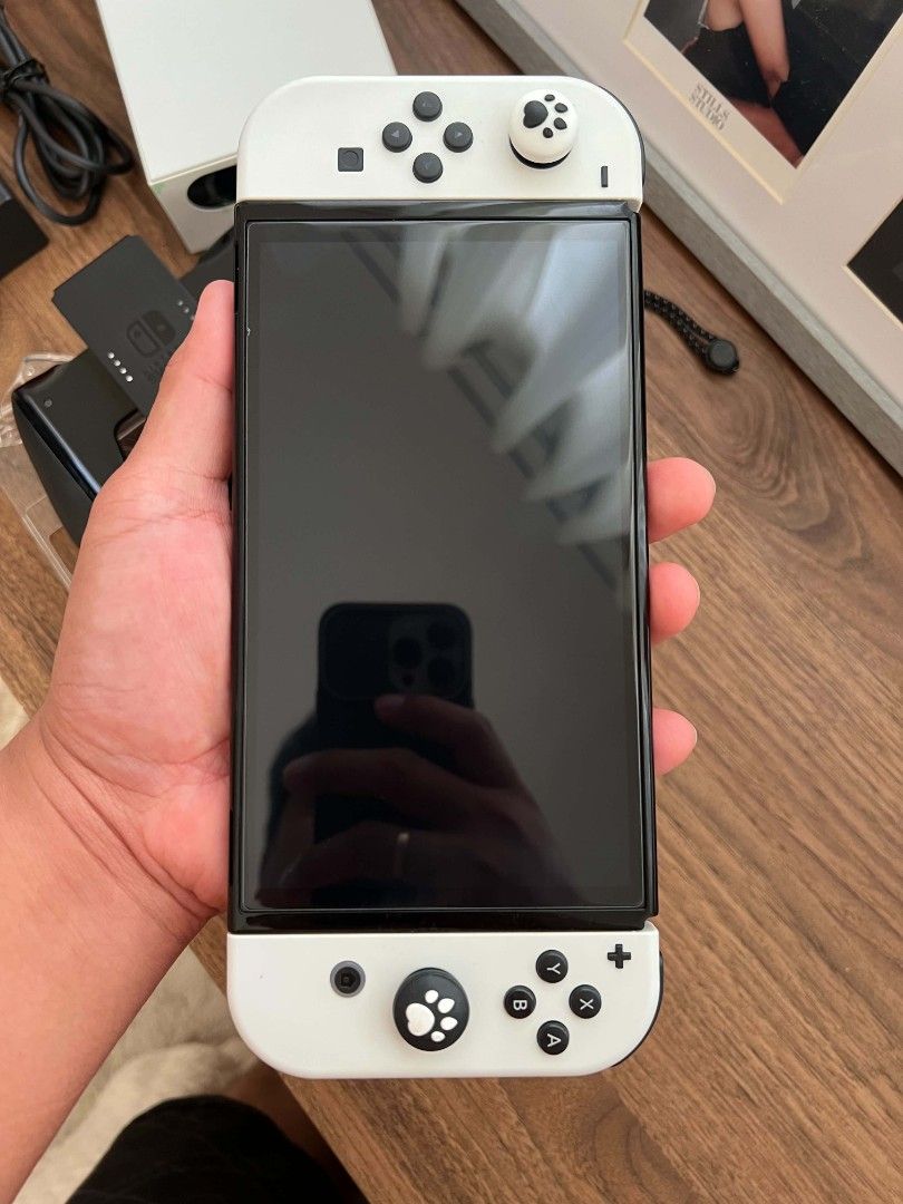 Nintendo Switch OLED White Console Full Bundle (Category: Nintendo) located in Cavite. Submitted by pitchblack012 (Listing ID 1467613943, Image 2). Description: - Nintendo Switch OLED Console (White) - 100% working condition, zero issues - Complete with original docking station, power adapter, and HDMI cable - Includes White Joy-Con controllers with grip attachments and wrist straps - Pre-installed cute cat paw thumb grips for extra comfort and s