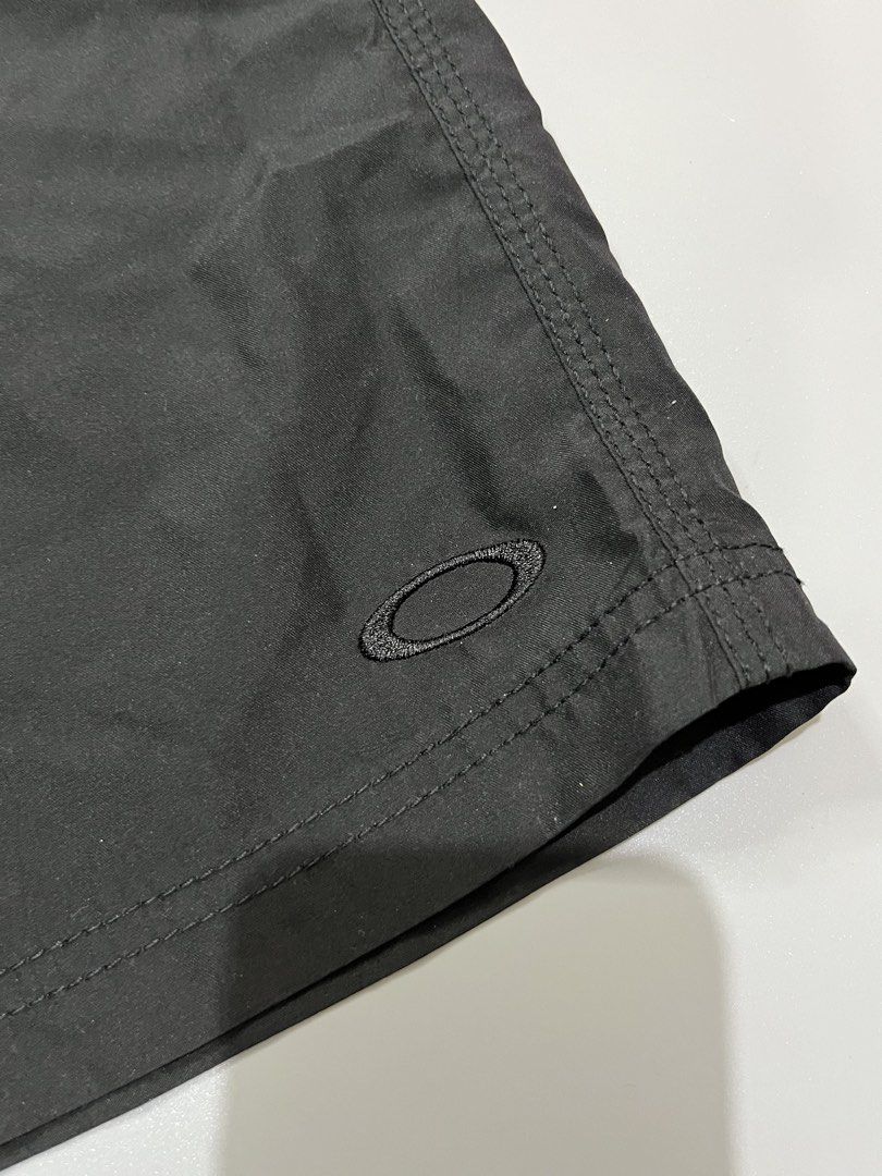 Oakley Black Board Shorts Size 32 (Category: Swim Trunks & Board Shorts) located in Manila. Submitted by jorgemabelin2001 (Listing ID 1467759891, Image 3). Description: - Brand: Oakley - Size: 32 - Color: Solid black - Waist: Adjustable drawstring with branded aglets - Storage: Back pocket featuring a built-in key loop - Details: Subtle embroidered ellipse logo on the lower leg - Authenticity: Interior waist tag displaying size and manufacturing 