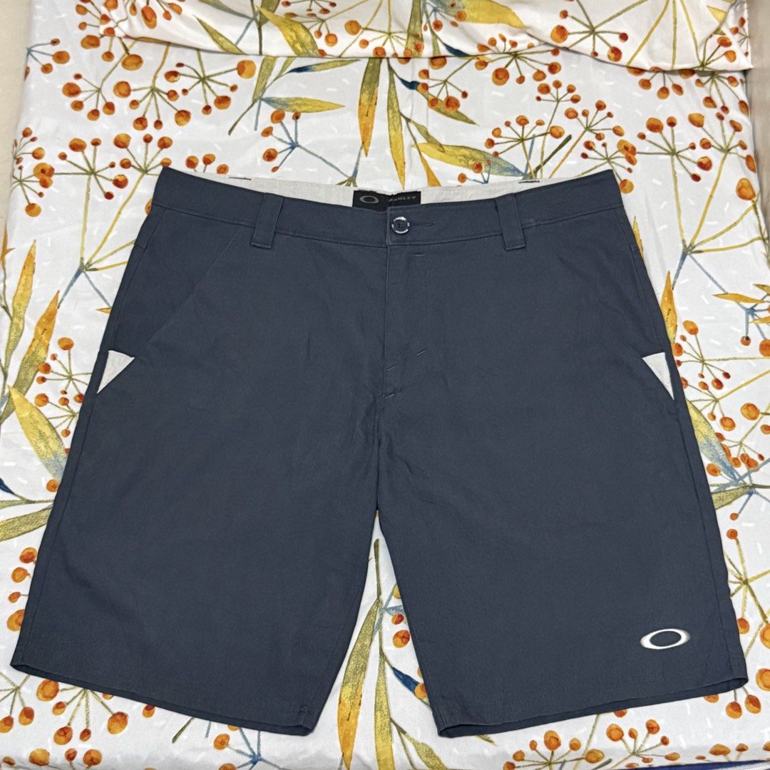 Oakley dark grey men's shorts size 36W (Category: Shorts) located in Manila. Submitted by coolphoenix.0 (Listing ID 1467721613, Image 1). Description: - Brand: Oakley - Color: Dark Grey - Size: 36W (Regular Fit) - Closure: Standard button closure with belt loops - Pockets: Two front pockets with contrasting trim, two back pockets with white piping and Oakley text tag - Branding: Subtle embroidered Oakley icon logo on the lower left leg - Conditio