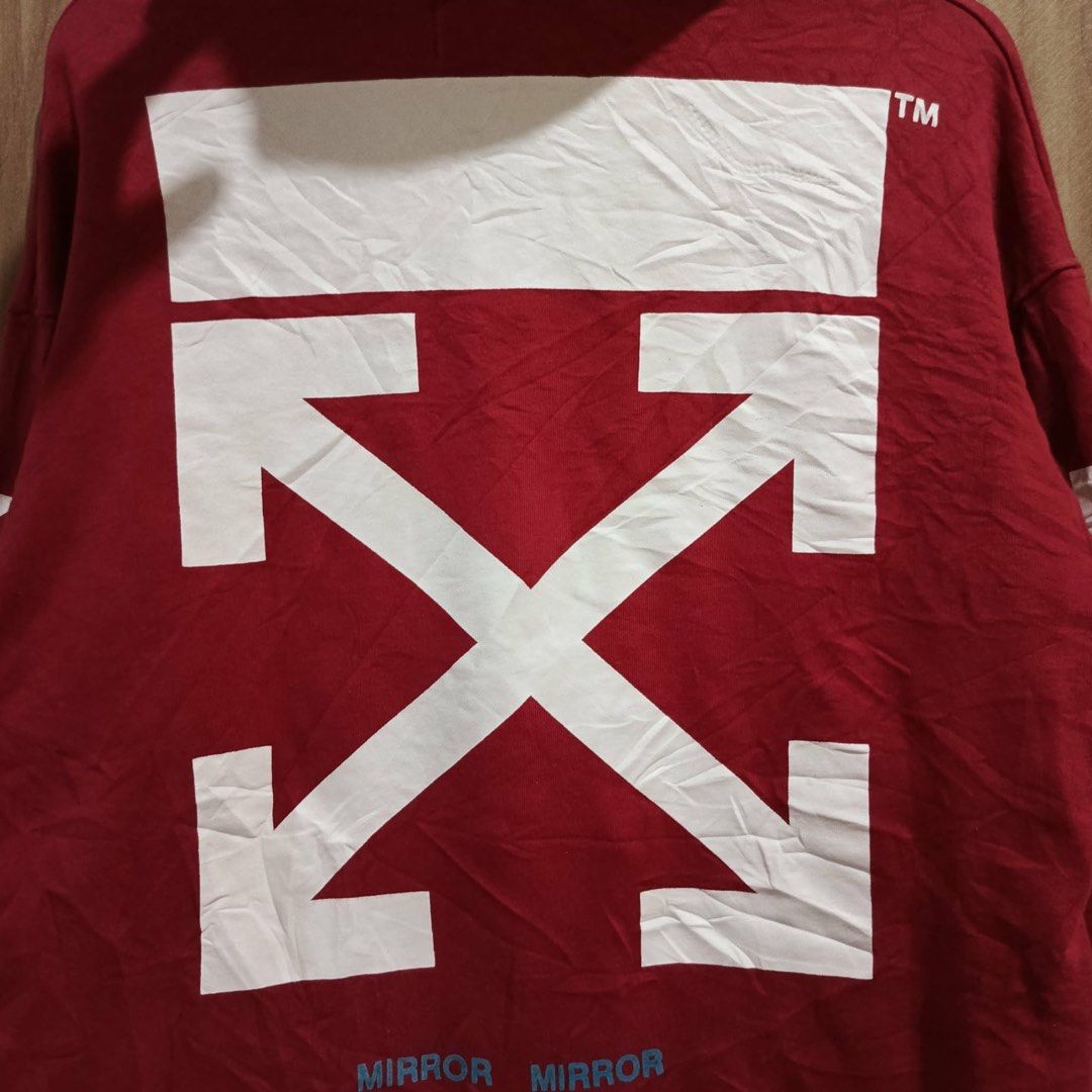 Off-White Red Mirror Mirror Hoodie (Category: Hoodies) located in Batangas. Submitted by phthriftpingzz (Listing ID 1467696993, Image 3). Description: - Brand: Off-White - Color: Red - Size: Large - Design: Large white diagonal arrows and 'MIRROR MIRROR' text on the back - Details: Small white 'OFF' text on chest, striped patterns on sleeves, and drawstring hood - Features: Front kangaroo pocket and white neck label - Style: Classic streetwear.