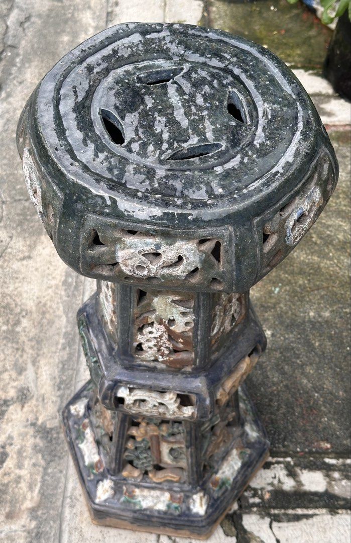 Old Chinese Ceramic Pedestal (Category: Pots & Planters) located in Quezon City. Submitted by anjherga27 (Listing ID 1467711122, Image 3). Description: - Type: Heavy ceramic stool / plant stand - Design: Multi-sided pillar shape with traditional cut-out lattice panels and dark glaze - Features: Flat top with four vent holes, earthy tones visible through the glaze - Versatility: Ideal as extra seating or a plant stand for the garden or living room