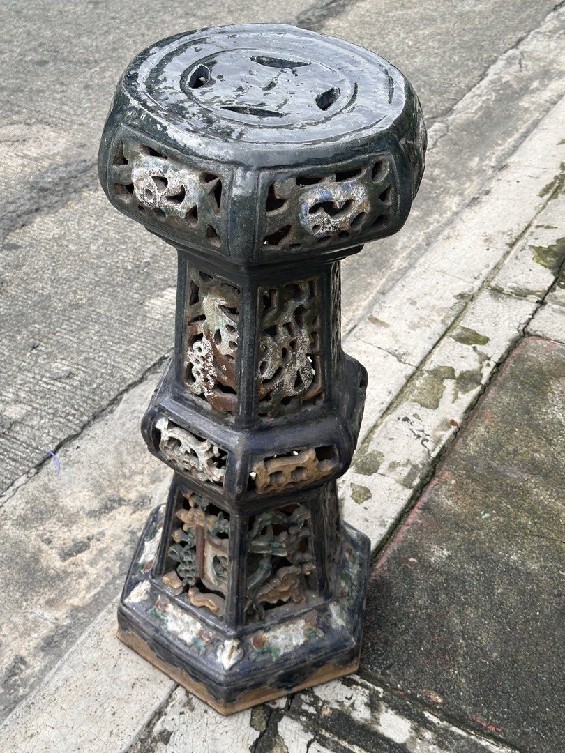 Old Chinese Ceramic Pedestal (Category: Pots & Planters) located in Quezon City. Submitted by anjherga27 (Listing ID 1467711122, Image 2). Description: - Type: Heavy ceramic stool / plant stand - Design: Multi-sided pillar shape with traditional cut-out lattice panels and dark glaze - Features: Flat top with four vent holes, earthy tones visible through the glaze - Versatility: Ideal as extra seating or a plant stand for the garden or living room